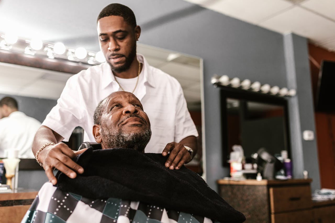 A barber styling a client's hair in a professional barber shop setting, reflecting skill and care.